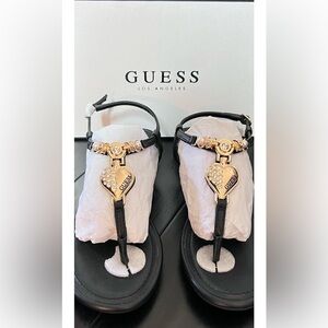 Guess Women’s T-Strap Sandal with gold hardware accents.